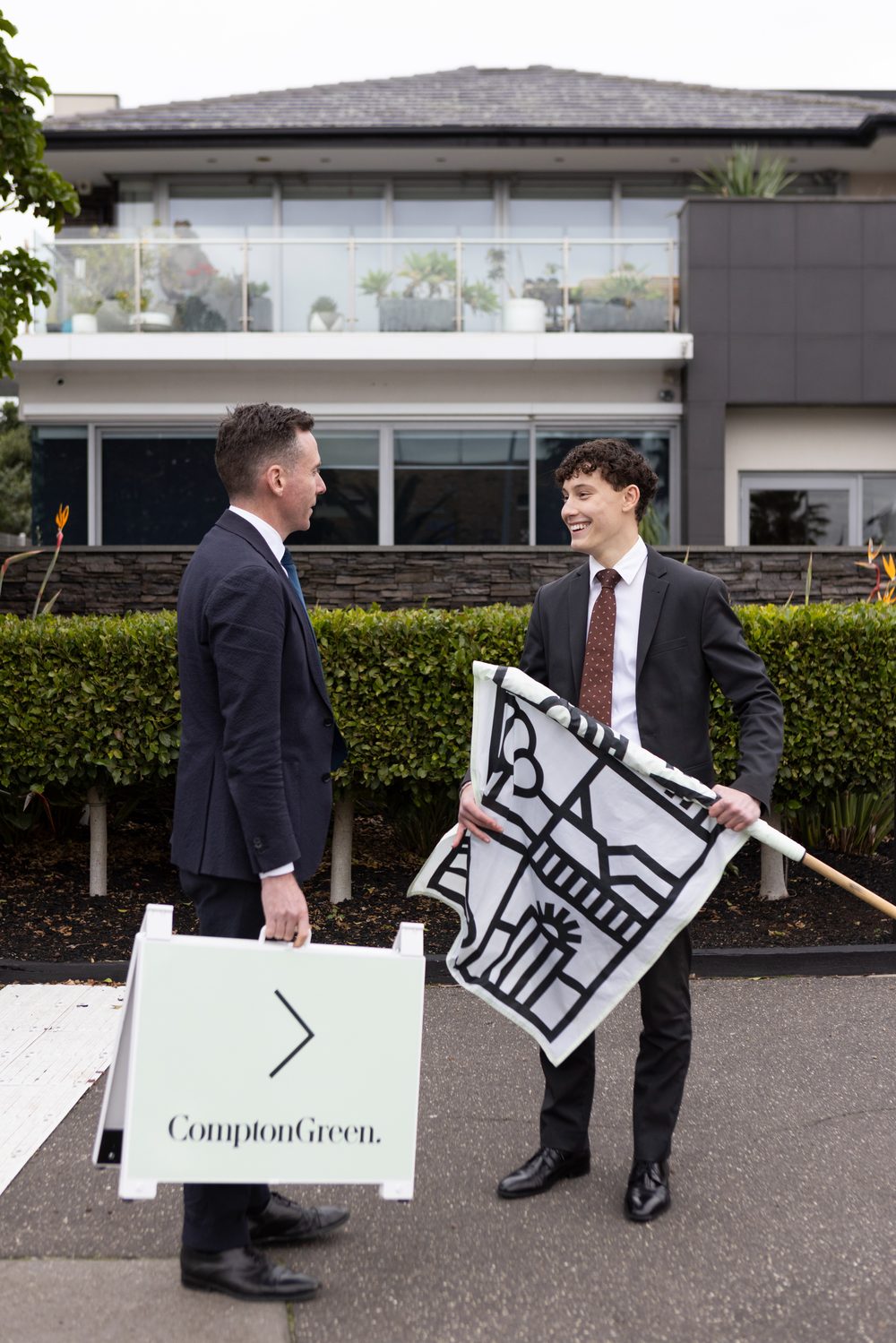 Compton Green agents setting up a signboard and flag outside an Inner West home